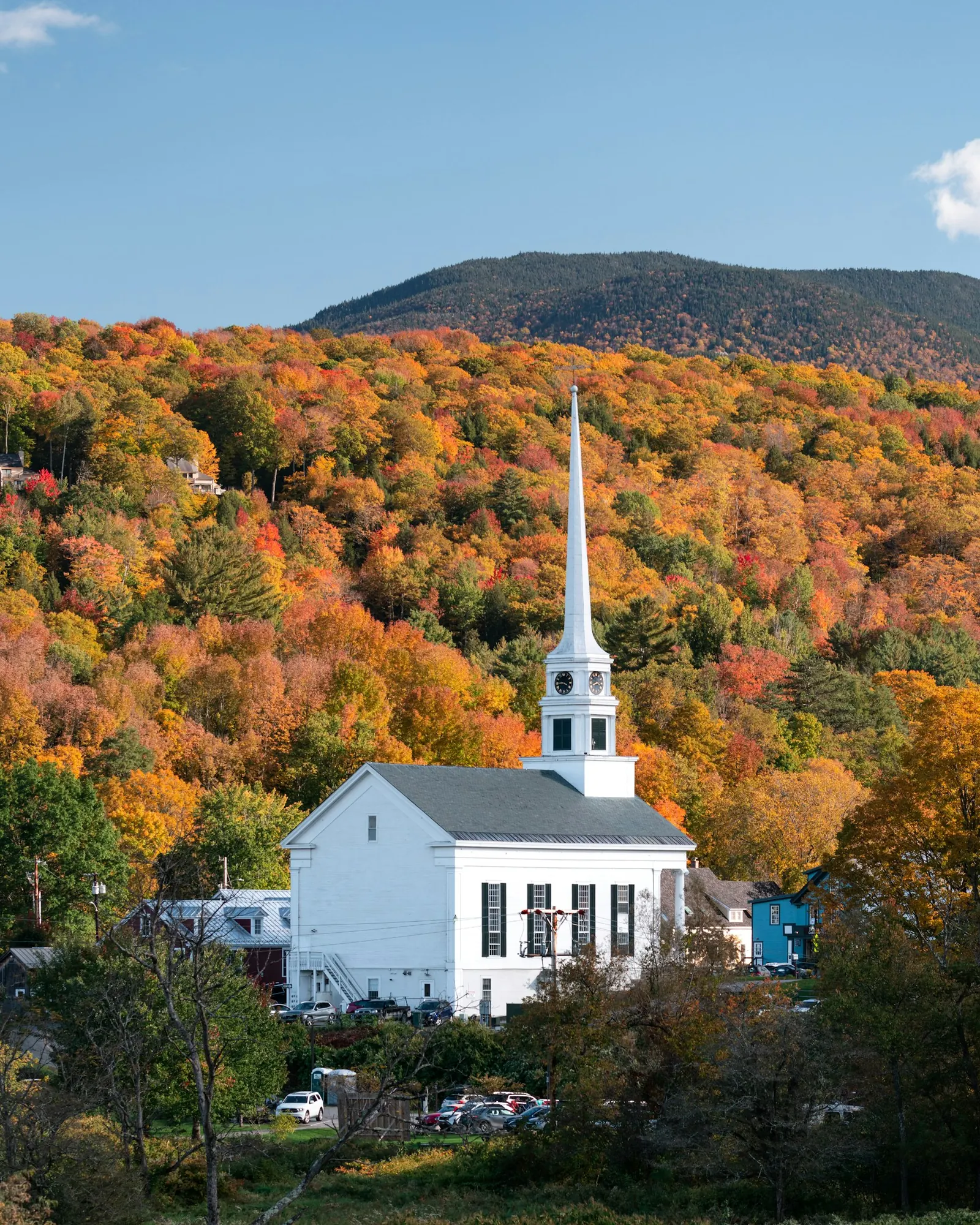 White steepled church surrounded by fall foliage
